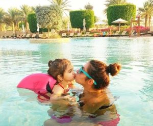 Child wearing SwimFin swimming aid in pool with mother